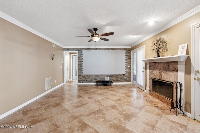 unfurnished living room with a tile fireplace, ceiling fan, brick wall, a textured ceiling, and ornamental molding