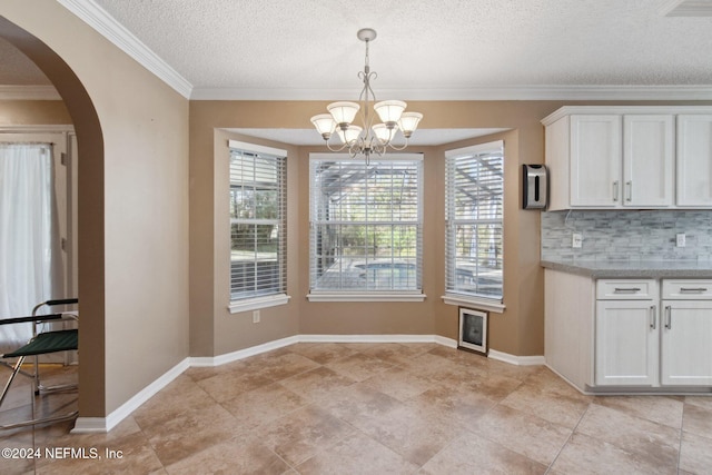 unfurnished dining area with ornamental molding, a textured ceiling, and an inviting chandelier