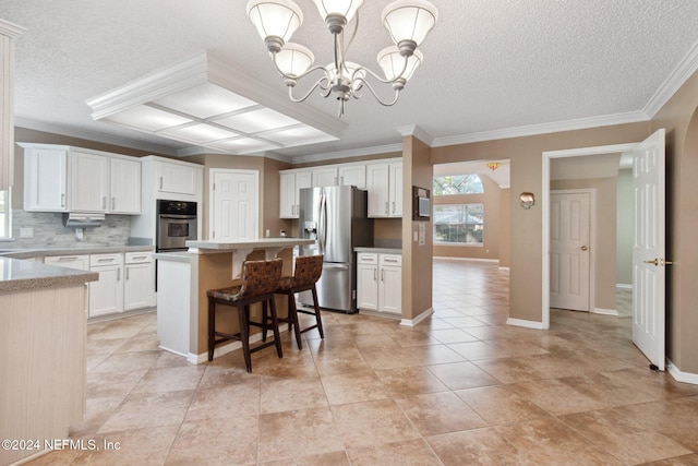 kitchen with appliances with stainless steel finishes, crown molding, a center island, white cabinetry, and hanging light fixtures