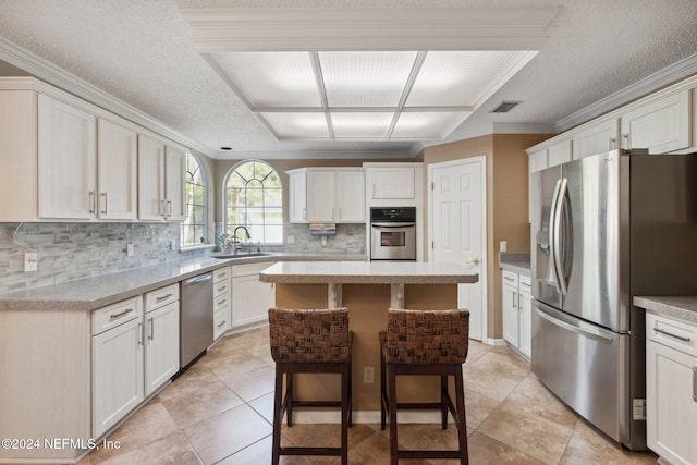 kitchen featuring a breakfast bar, sink, crown molding, a kitchen island, and stainless steel appliances