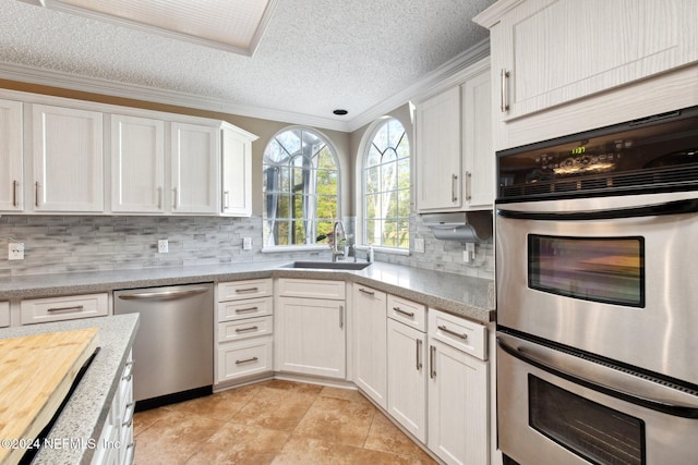 kitchen featuring appliances with stainless steel finishes, a textured ceiling, crown molding, sink, and white cabinetry