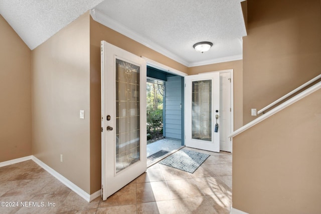 tiled foyer entrance with french doors, a textured ceiling, and ornamental molding