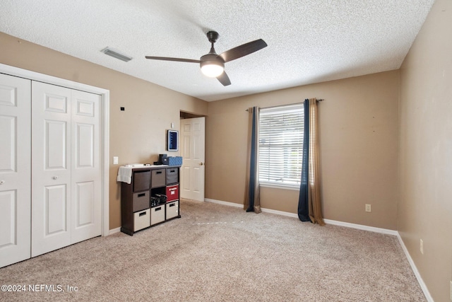 bedroom with ceiling fan, a closet, light carpet, and a textured ceiling