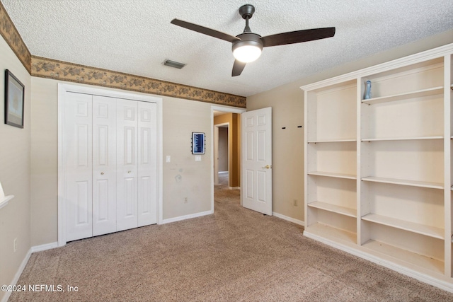 unfurnished bedroom featuring ceiling fan, a closet, carpet floors, and a textured ceiling