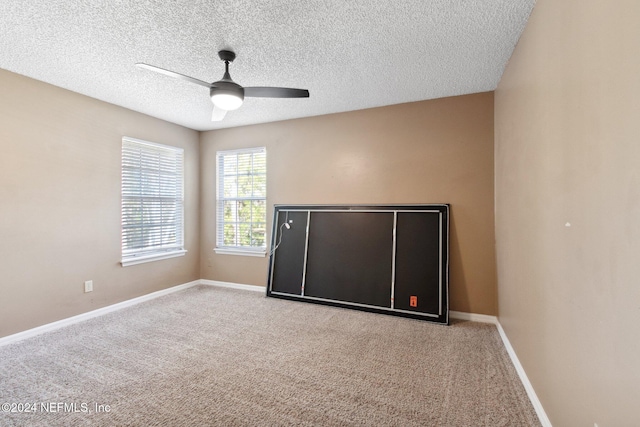 carpeted empty room featuring ceiling fan and a textured ceiling