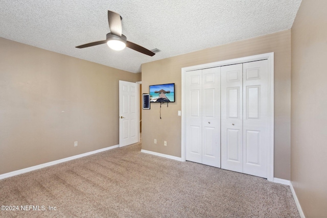 unfurnished bedroom featuring ceiling fan, carpet floors, a textured ceiling, and a closet