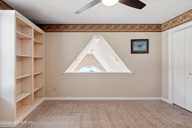 carpeted empty room with ceiling fan and a textured ceiling