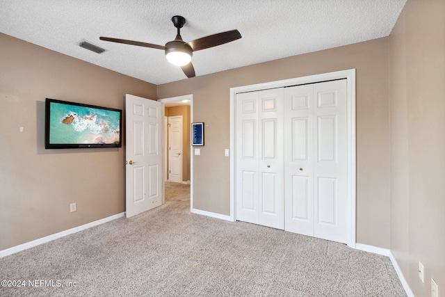 unfurnished bedroom with ceiling fan, a closet, carpet, and a textured ceiling