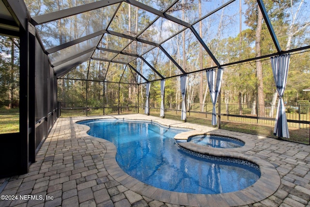 view of pool with glass enclosure, a patio area, and an in ground hot tub