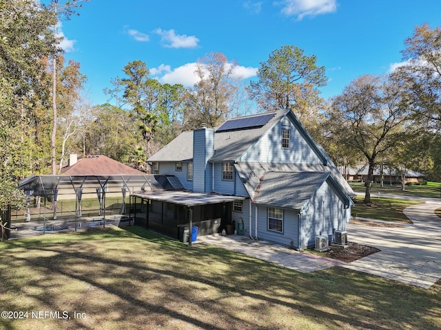 back of house featuring a sunroom, cooling unit, a lanai, and a yard