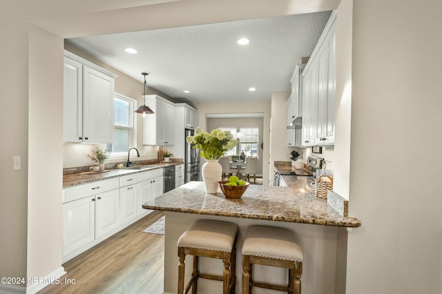 kitchen featuring white cabinetry, light wood-type flooring, kitchen peninsula, and a healthy amount of sunlight