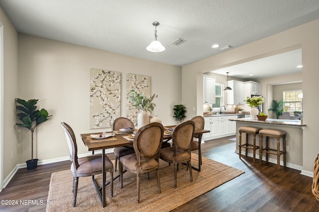 dining space featuring dark hardwood / wood-style flooring, a textured ceiling, and sink