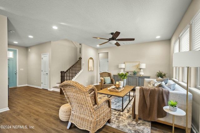 living room featuring a textured ceiling, ceiling fan, and dark hardwood / wood-style floors