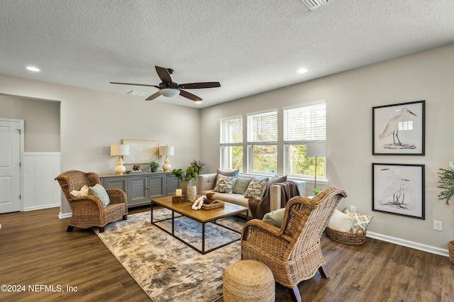 living room with a textured ceiling, ceiling fan, and dark hardwood / wood-style floors