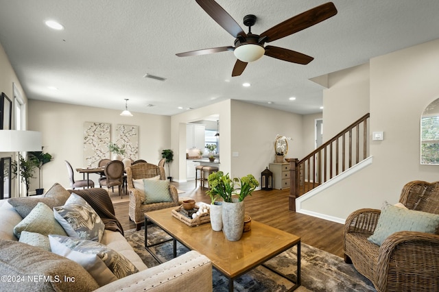 living room with ceiling fan, wood-type flooring, and a textured ceiling