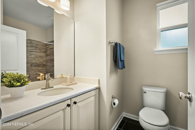 bathroom featuring tile patterned flooring, vanity, toilet, and tiled shower