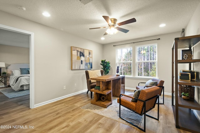 living area featuring ceiling fan, light hardwood / wood-style floors, and a textured ceiling