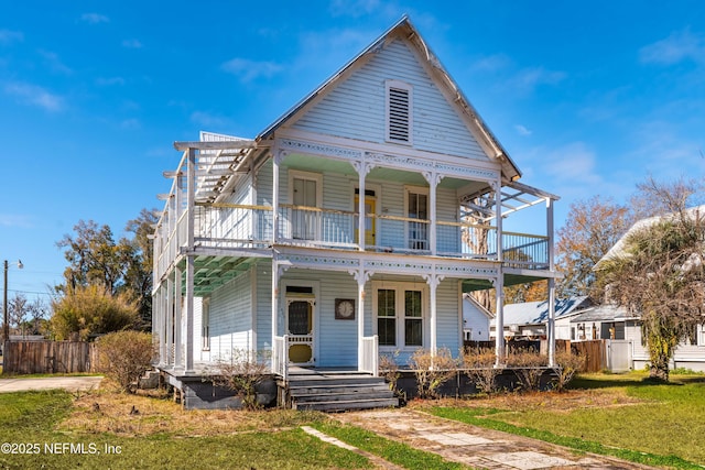 victorian house featuring a front yard, a balcony, and a porch