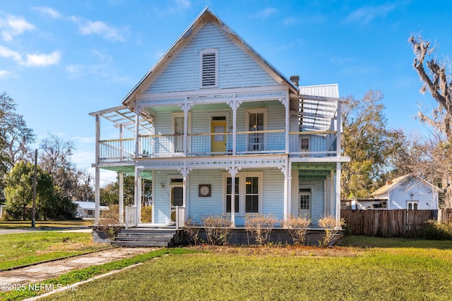 view of front of house featuring a front yard, a balcony, and covered porch