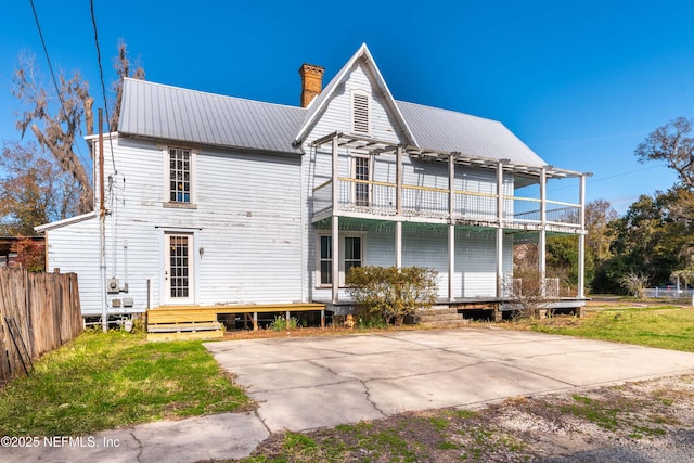 rear view of house featuring a balcony and a lawn