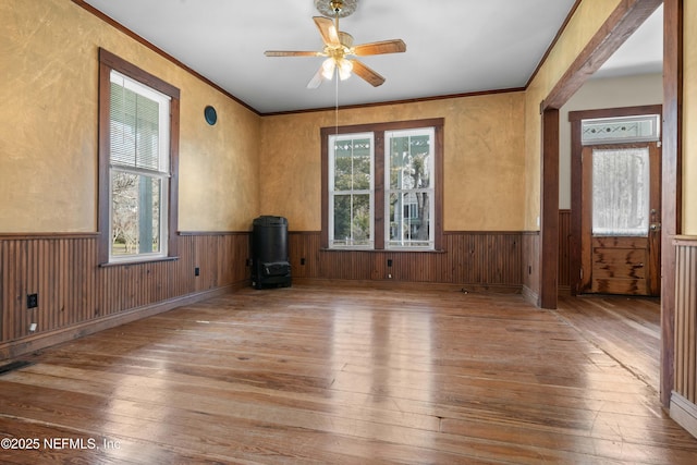 unfurnished living room featuring wood-type flooring, ornamental molding, and ceiling fan