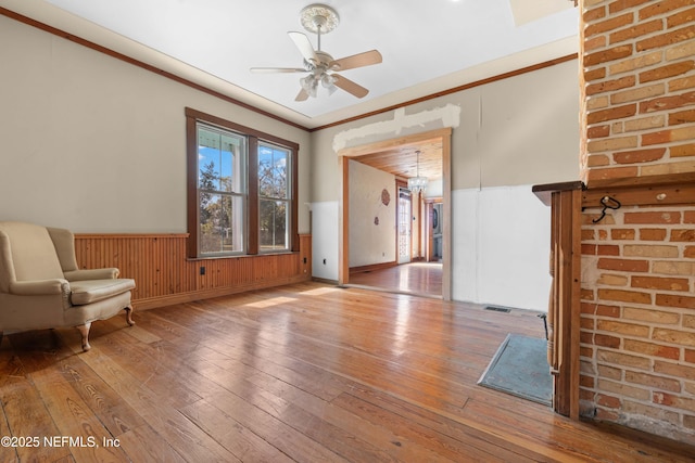 unfurnished living room featuring hardwood / wood-style floors, ornamental molding, and ceiling fan