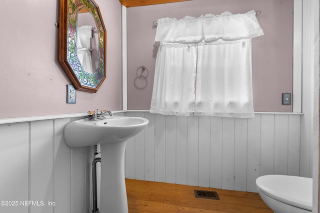 bathroom featuring wooden walls and toilet