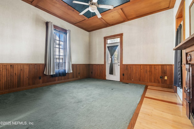 empty room with coffered ceiling, a wealth of natural light, wooden ceiling, and ceiling fan