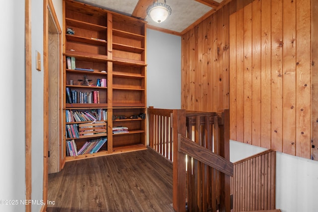 hallway with crown molding, dark wood-type flooring, and wooden walls