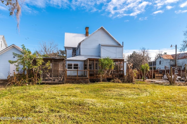 back of house featuring a lawn, a sunroom, and a deck