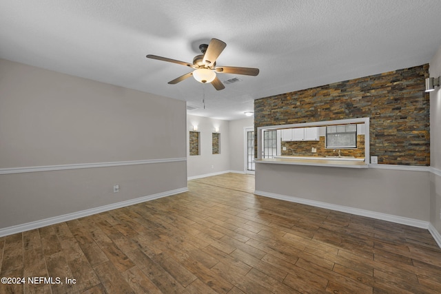 unfurnished living room with ceiling fan, wood-type flooring, and a textured ceiling