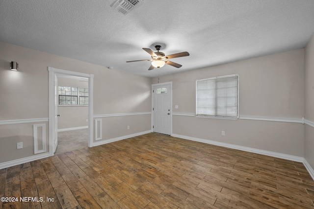 unfurnished room with a textured ceiling, dark hardwood / wood-style floors, and ceiling fan