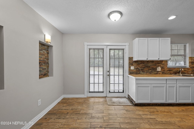 kitchen with french doors, backsplash, sink, light hardwood / wood-style flooring, and white cabinets