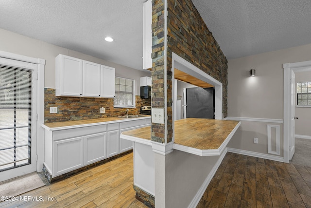 kitchen with light wood-type flooring, tasteful backsplash, and white cabinetry