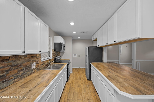 kitchen featuring white cabinetry, stainless steel appliances, wood counters, backsplash, and light wood-type flooring