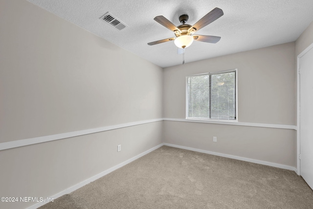 carpeted spare room with a textured ceiling and ceiling fan