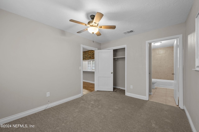 unfurnished bedroom featuring light carpet, connected bathroom, a closet, and ceiling fan