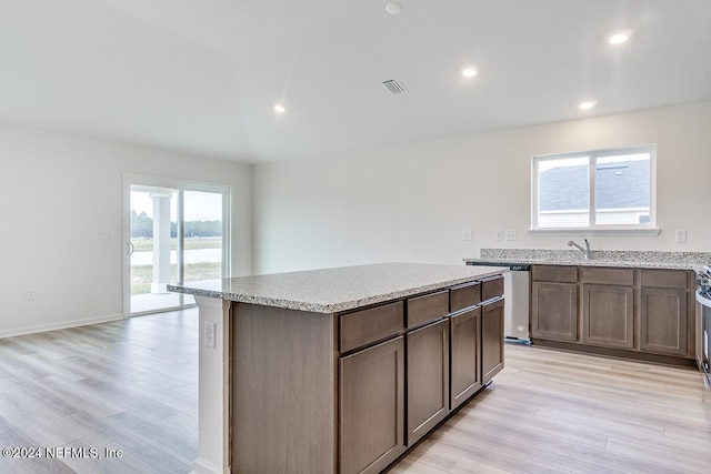 kitchen with stainless steel dishwasher, a center island, and light hardwood / wood-style floors