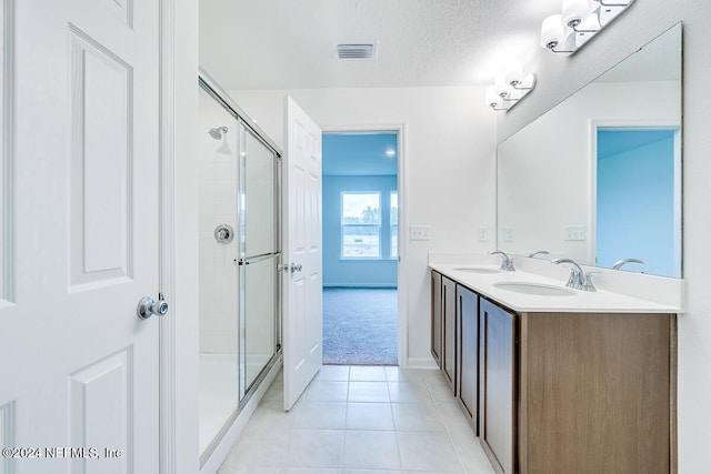 bathroom featuring tile patterned flooring, vanity, a shower with shower door, and a textured ceiling