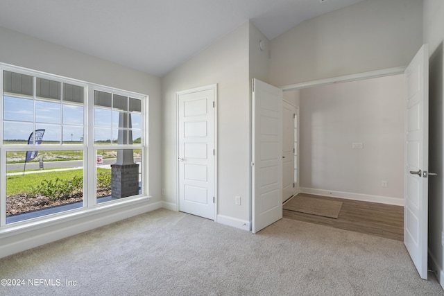 unfurnished bedroom with light colored carpet and lofted ceiling