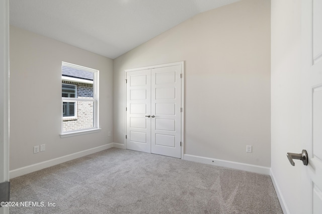 unfurnished bedroom with a closet, lofted ceiling, and light carpet