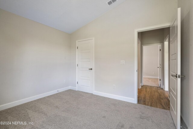 unfurnished bedroom with lofted ceiling and carpet floors