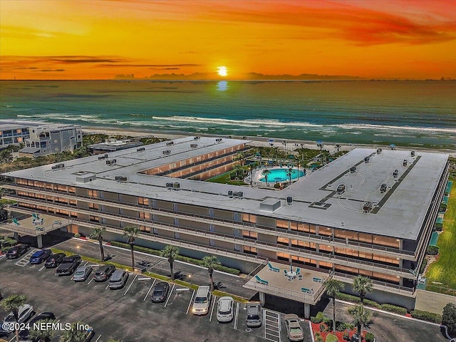 aerial view at dusk with a water view and a view of the beach