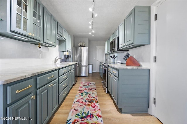 kitchen featuring decorative backsplash, light wood-type flooring, stainless steel appliances, and sink