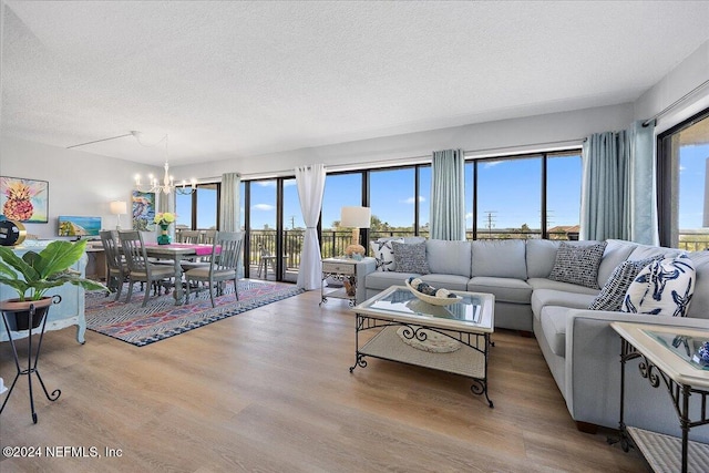 living room with a wealth of natural light, light hardwood / wood-style flooring, a textured ceiling, and an inviting chandelier