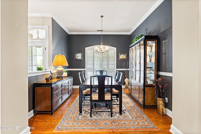 dining space featuring a chandelier, crown molding, baseboards, and wood finished floors