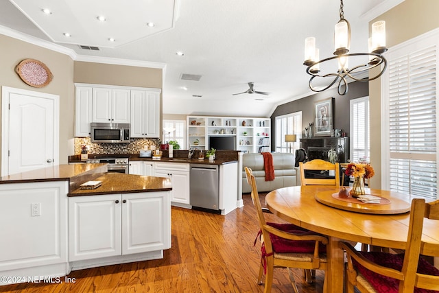 kitchen featuring visible vents, a healthy amount of sunlight, ceiling fan with notable chandelier, a fireplace, and stainless steel appliances