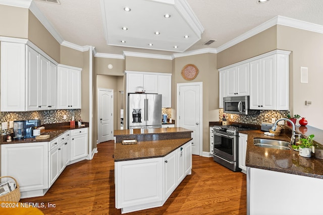 kitchen featuring visible vents, a sink, a kitchen island, wood finished floors, and appliances with stainless steel finishes