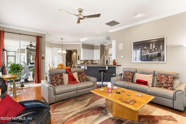 living area featuring visible vents, ceiling fan with notable chandelier, crown molding, and wood finished floors