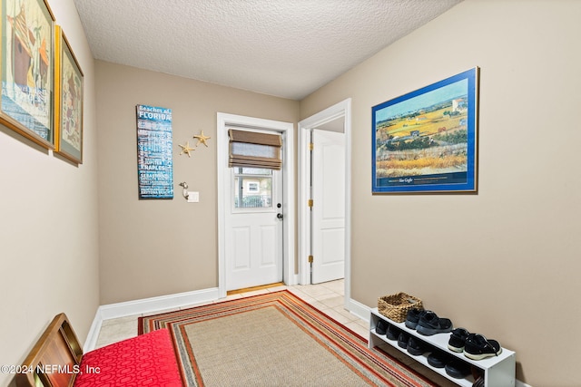 interior space with tile patterned floors, a textured ceiling, and baseboards